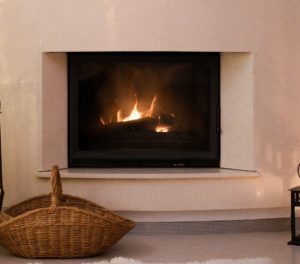 fireplace with burning logs. White mantle. Basket set in front for decor.