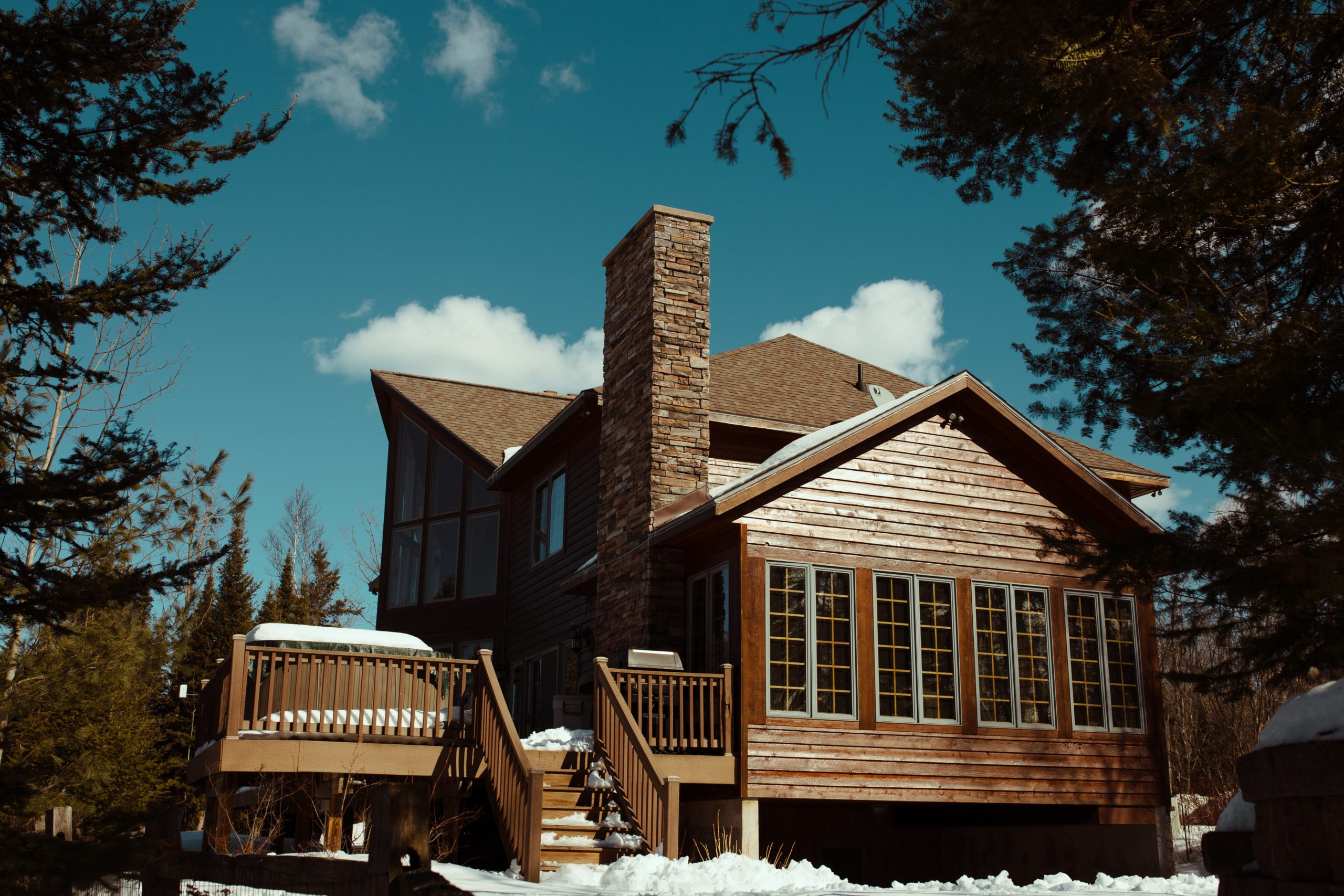 log home ready for chimney cleaning with snow around and blue sky 
