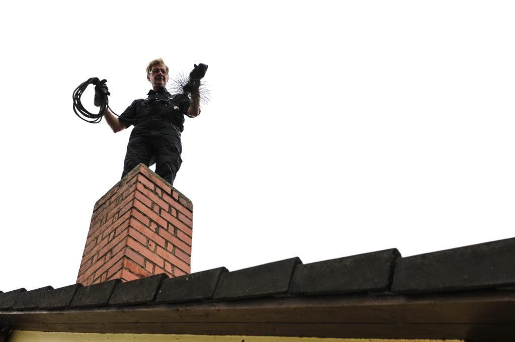 Chimney sweep is with his tool on the chimney to the fireplace to turn.