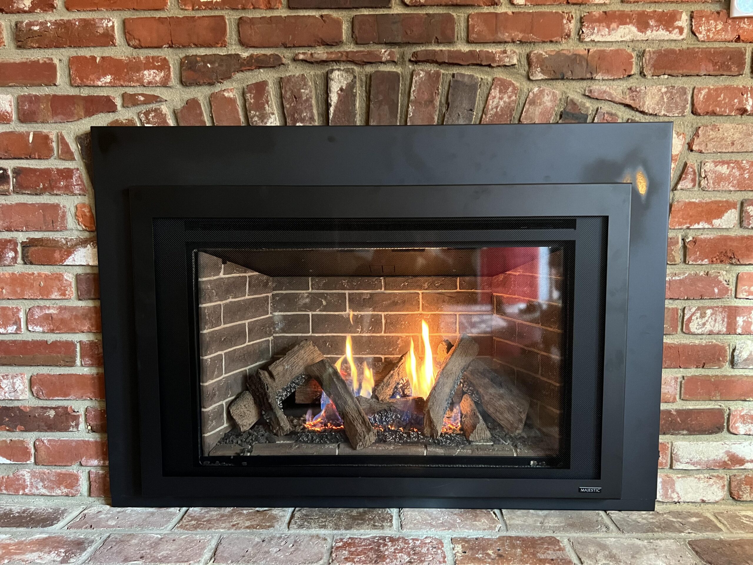 gas fireplace insert in red brick fireplace