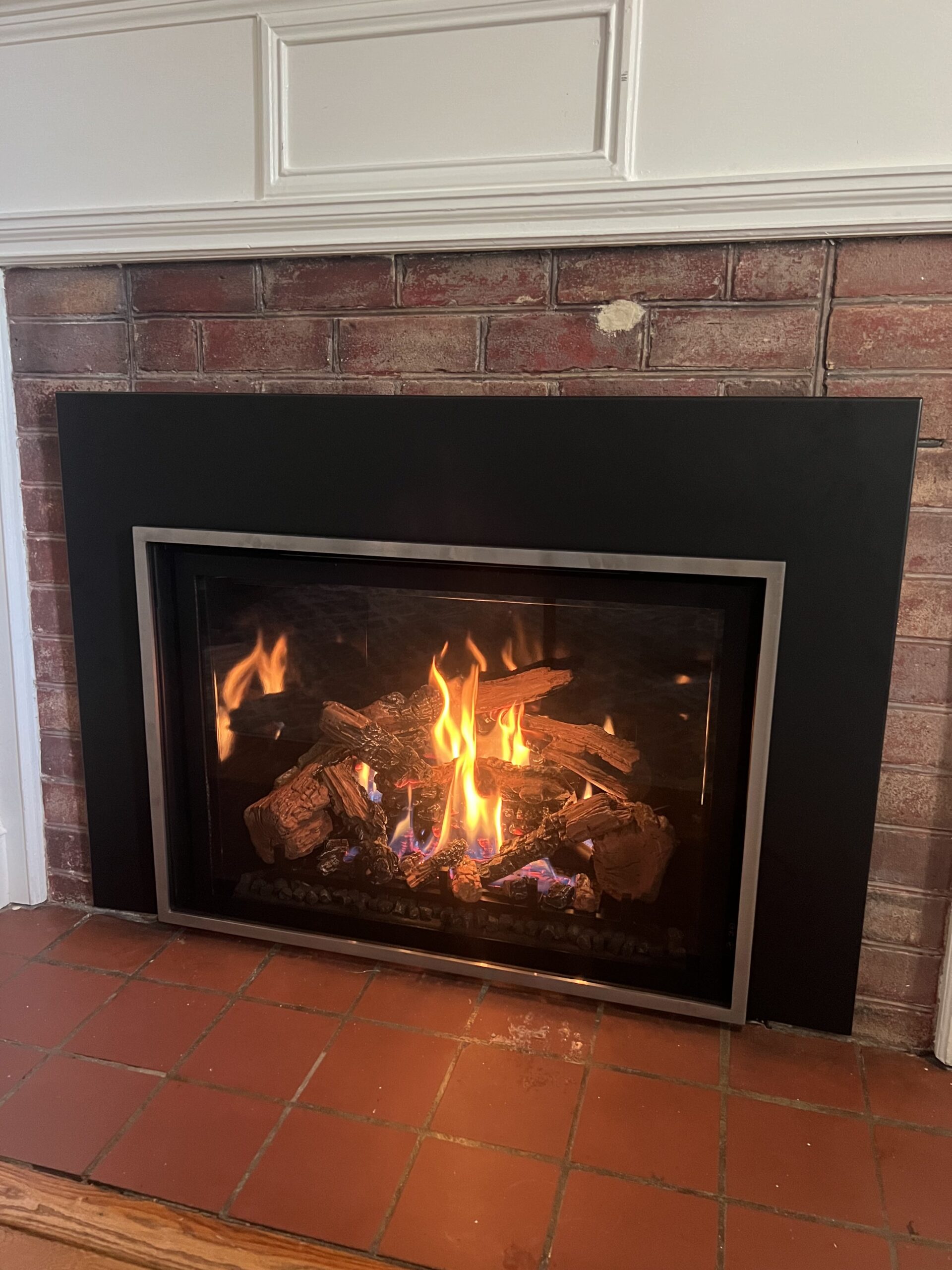 gas fireplace insert in a brick fireplace with a white mantel