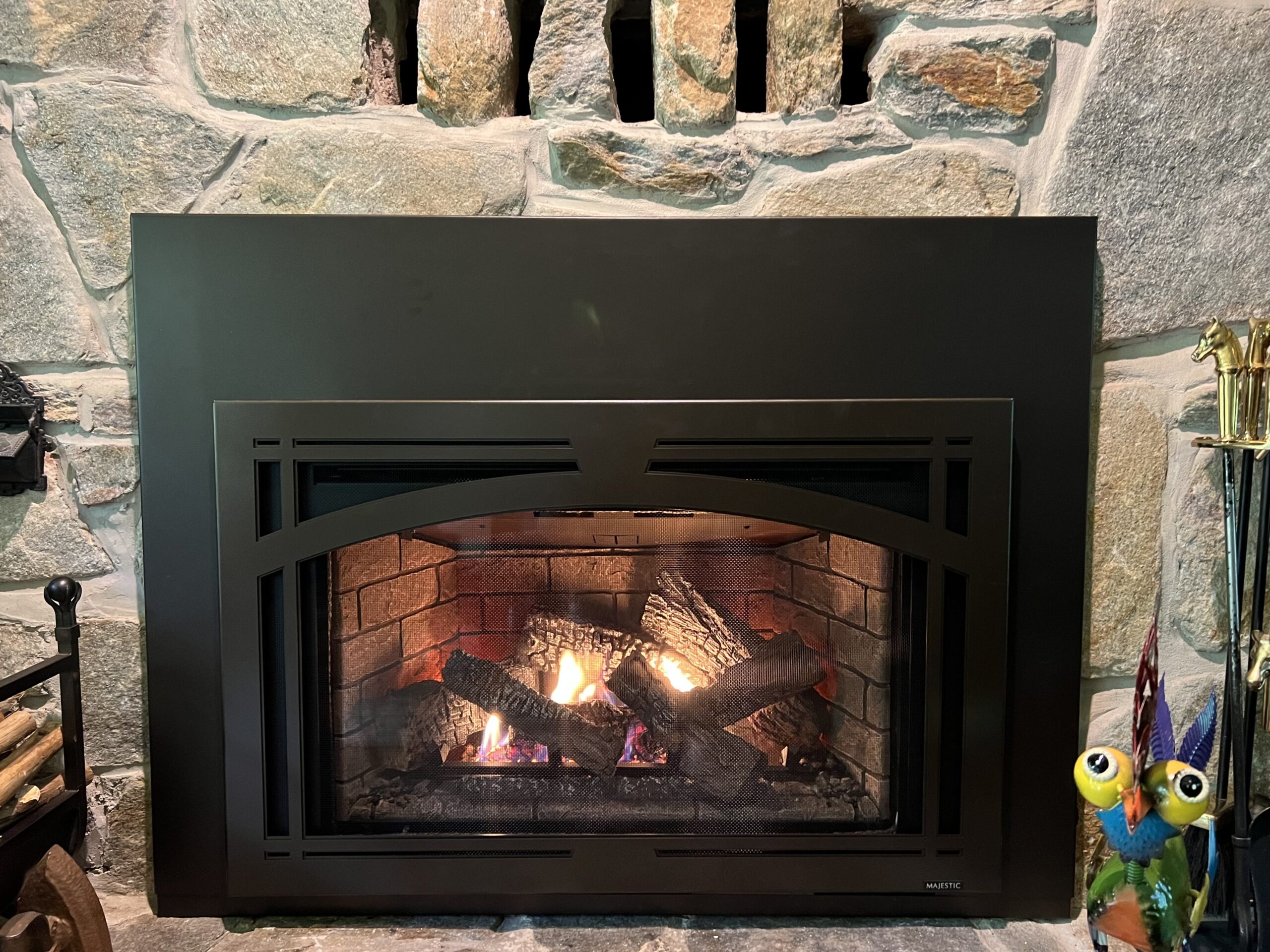 Gas fireplace insert in a wood burning fireplace with grey stone